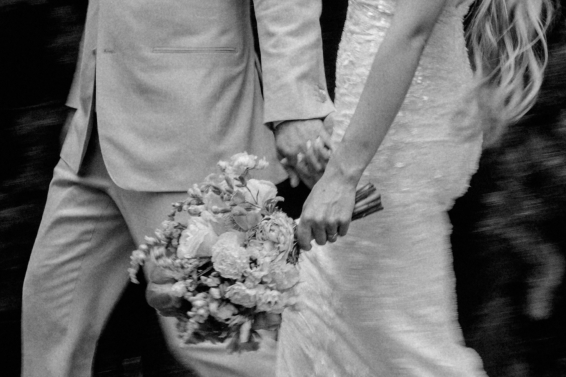 Schwarz-Weiß-Foto Detail von Brautpaar, das Hand-in-Hand spazieren geht